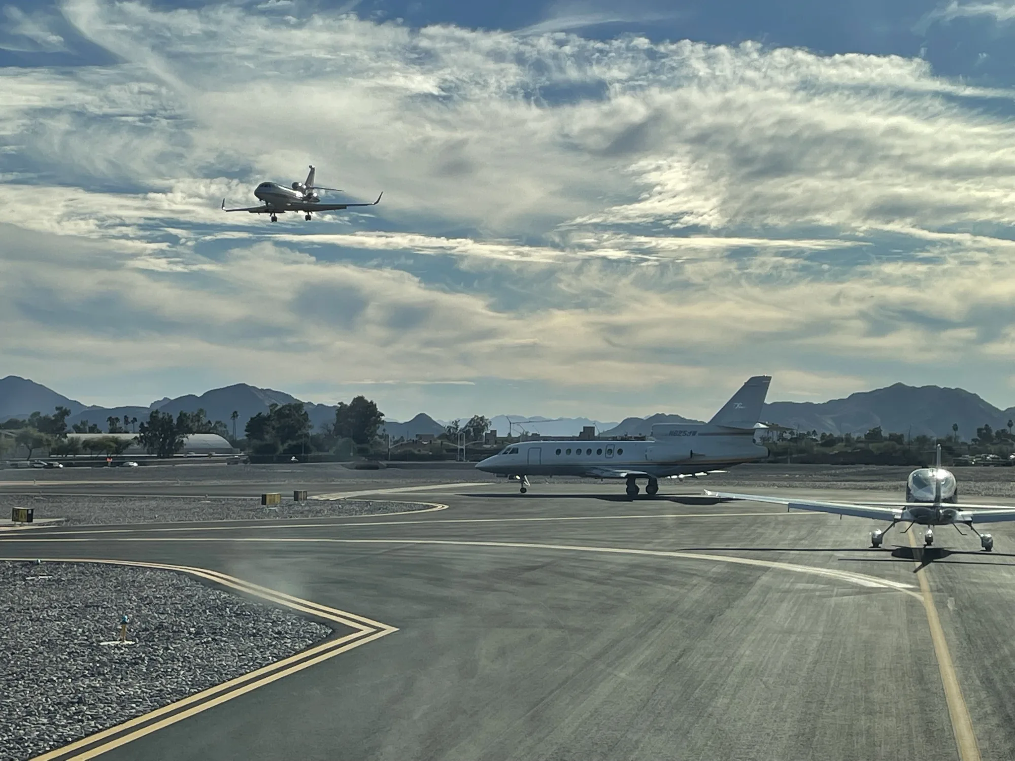 Several business jets on a ramp and on approach, comparing fractional jet ownership companies