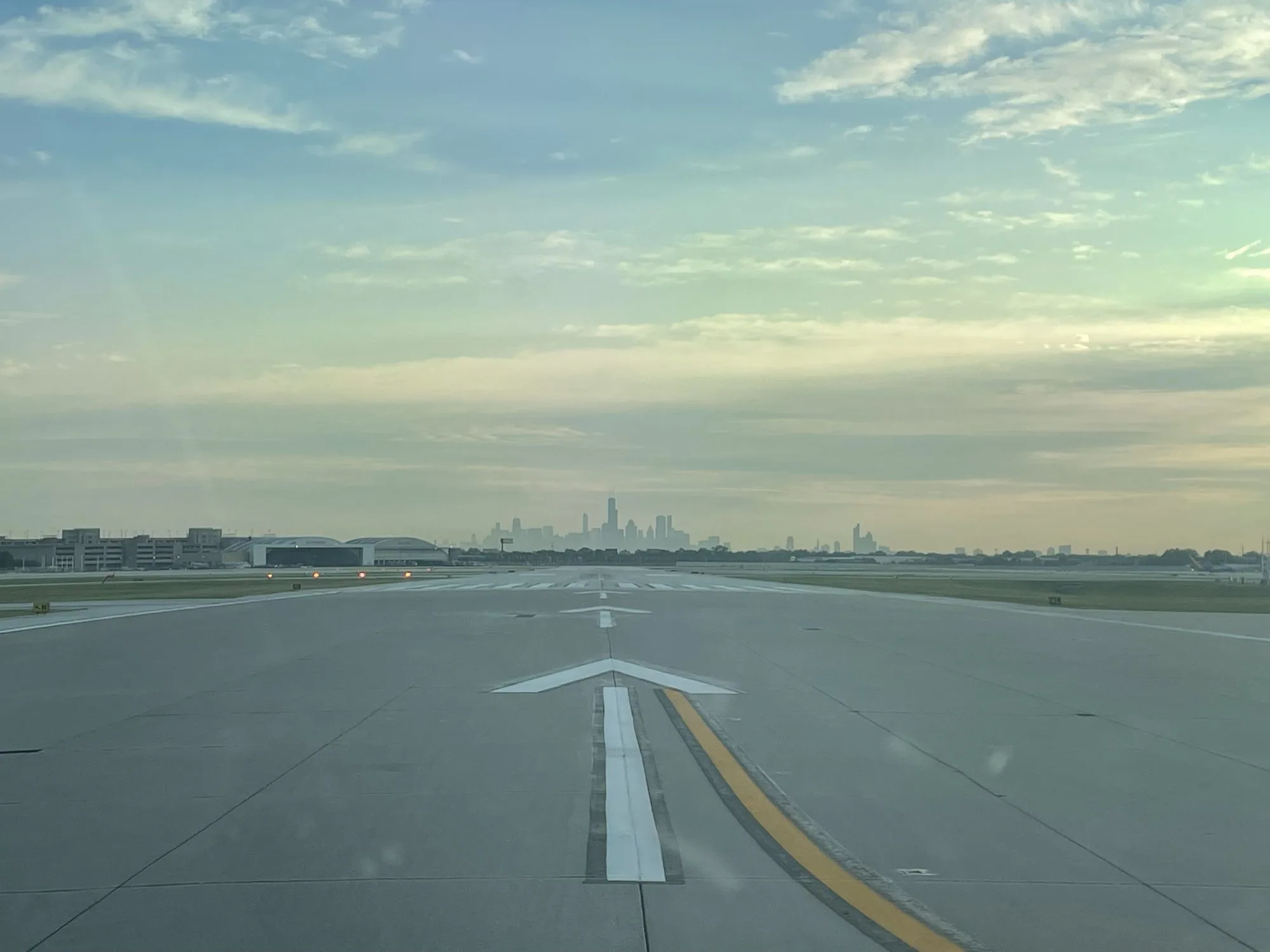 View down a taxiway toward a city skyline at dawn, choosing between fractional jet ownership companies